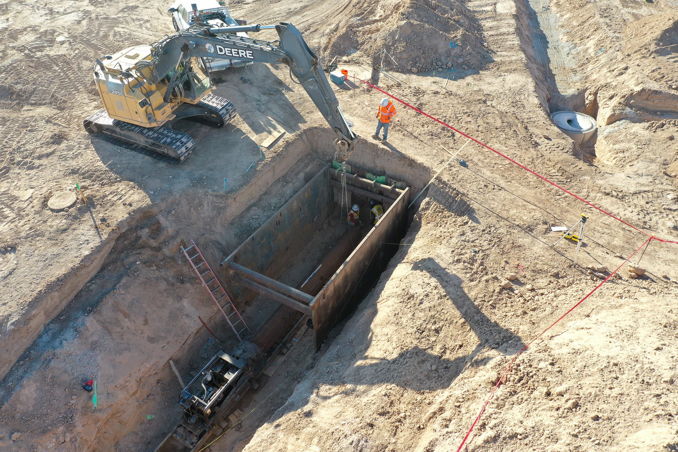 Crew working inside a trench box with an excavator overhead